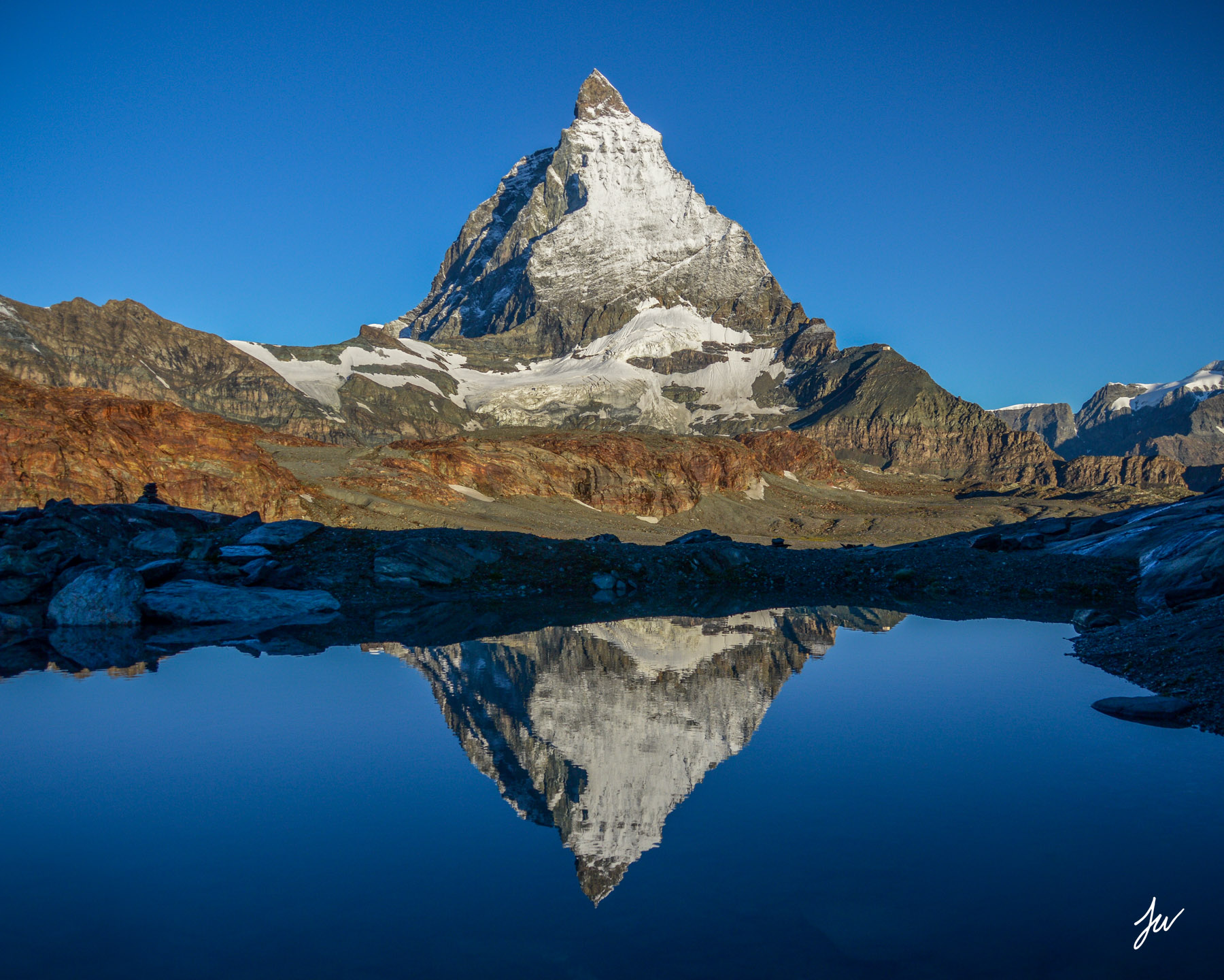 Image of a pristine Alpine lake reflecting snow-capped mountains